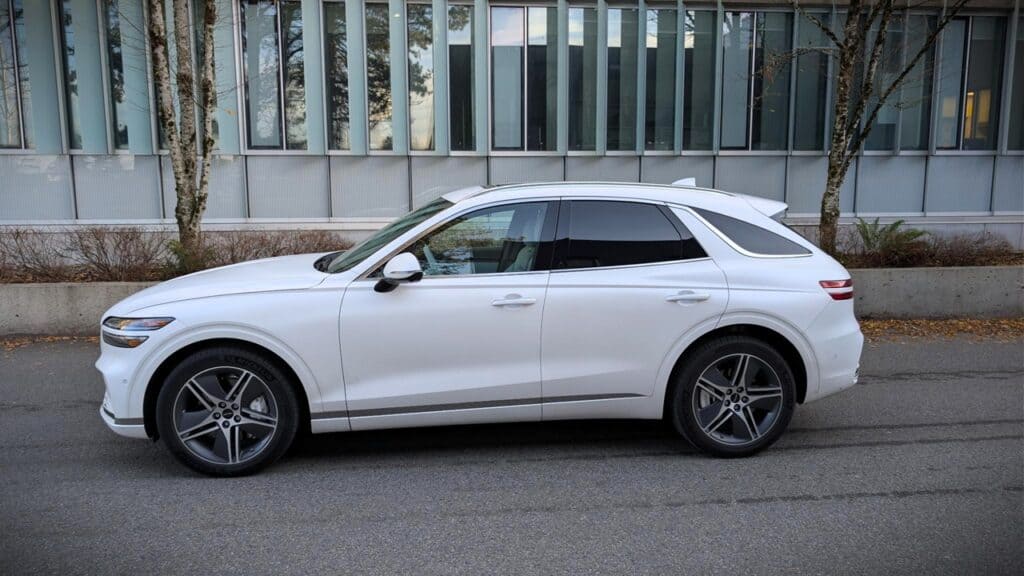 An elegant white 2026 Genesis Electrified GV70 Prestige SUV parked on a city street. The vehicle features sleek design, modern headlights, and premium alloy wheels, highlighting luxury and advanced el.