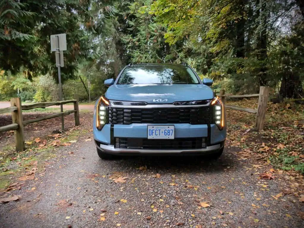 2026 Kia Sportage EX Hybrid Overview 7 Kia Sportage EX Hybrid parked on a forest trail, showcasing its modern design and eco-friendly hybrid technology. Perfect for outdoor adventures and urban driving with advanced features.