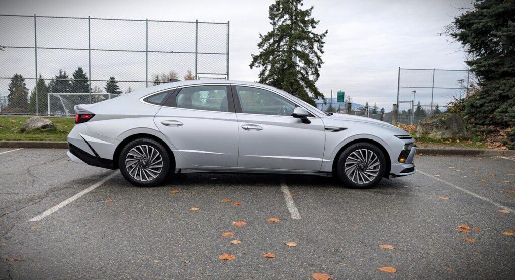 A sleek 2026 Hyundai Sonata Hybrid parked in an outdoor lot with a scenic background, showcasing modern design and eco-friendly features. Perfect for those interested in hybrid vehicles and automotive.