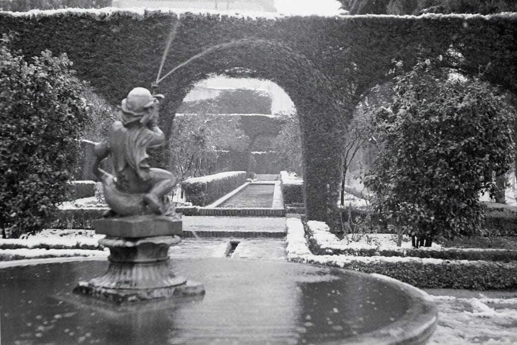 Ancient Italian garden featuring a charming fountain with a cherub statue, surrounded by well-maintained plants and stone pathways, exemplifying Italy's rich horticultural heritage.