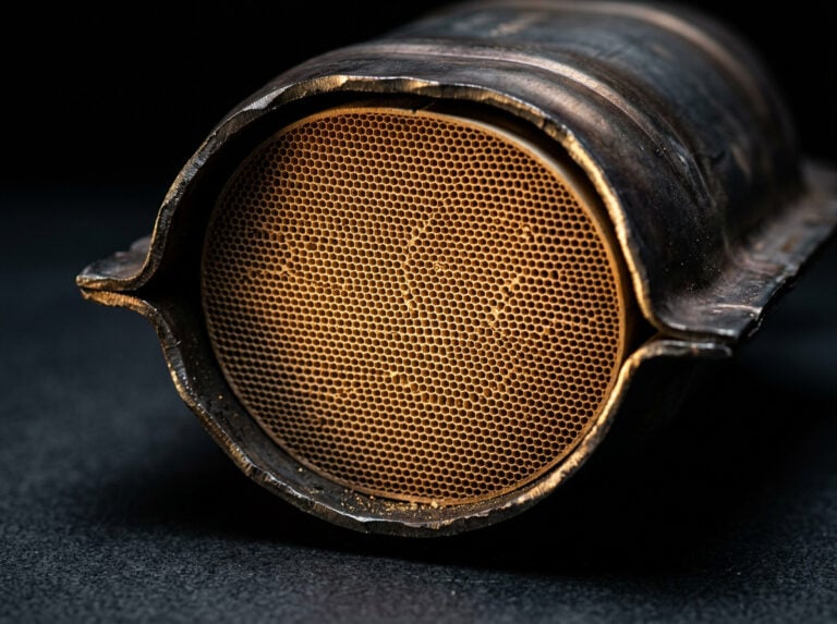 Close-up of a used catalytic converter showing the honeycomb structure, highlighting its importance in vehicle emissions control and scrap metal value.