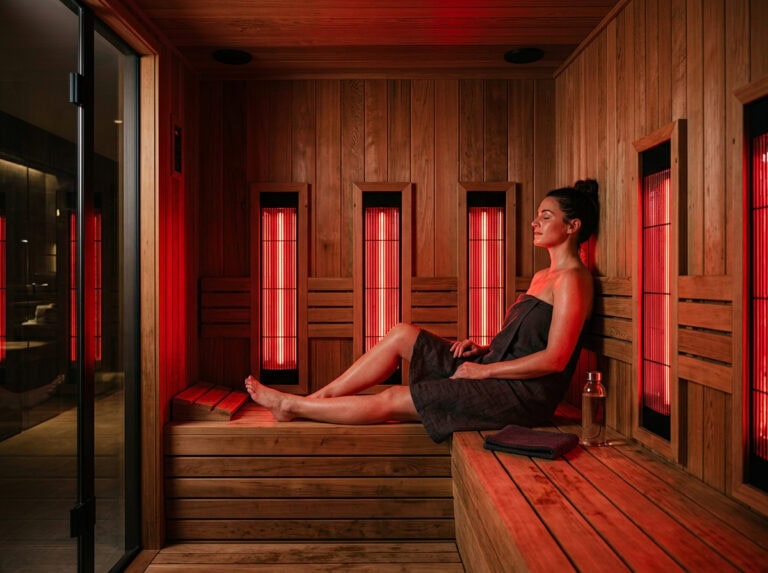 Woman sitting in an infrared sauna, enjoying the health benefits of infrared heat therapy for cardiovascular health and recovery.