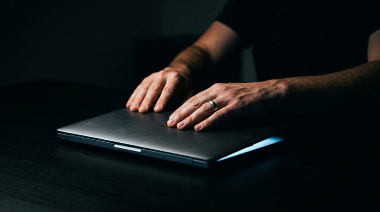 Person closing a laptop to unwind after work, emphasizing the importance of digital detox and relaxation routines.