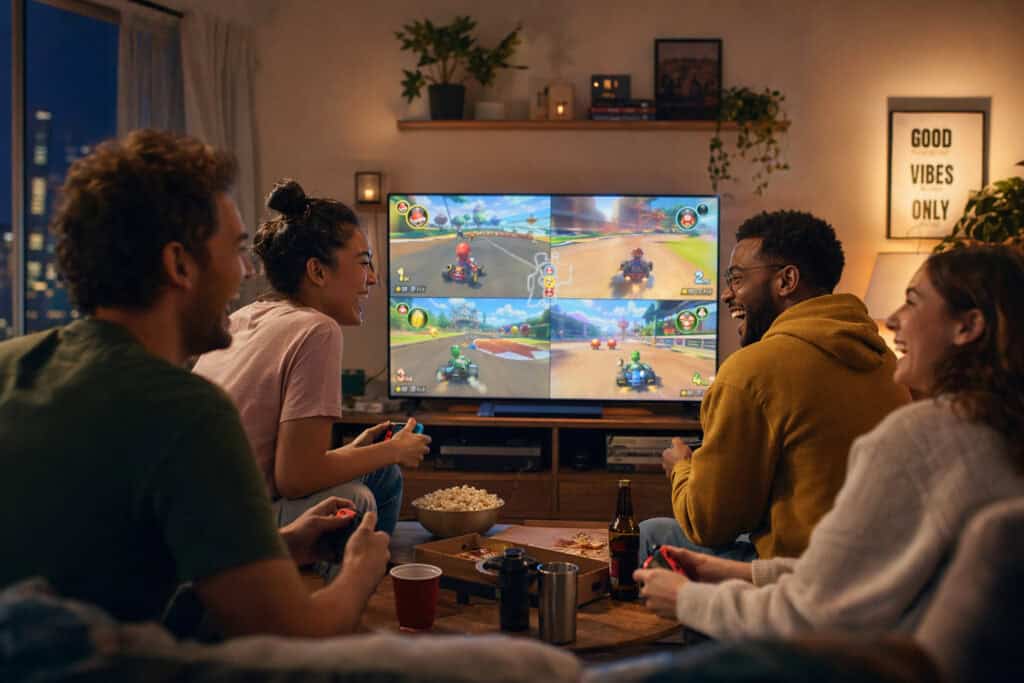 Group of friends enjoying a gaming night with a Nintendo Switch, playing Mario Kart together in a cozy living room setting.