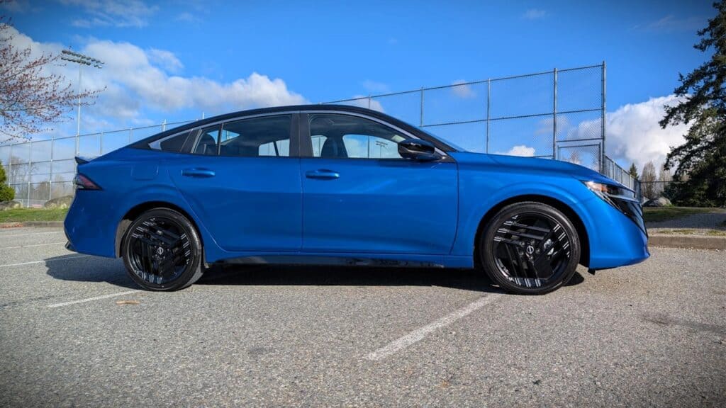 A sleek blue sedan parked on an outdoor asphalt lot under a partly cloudy sky, showcasing modern automotive design and style.