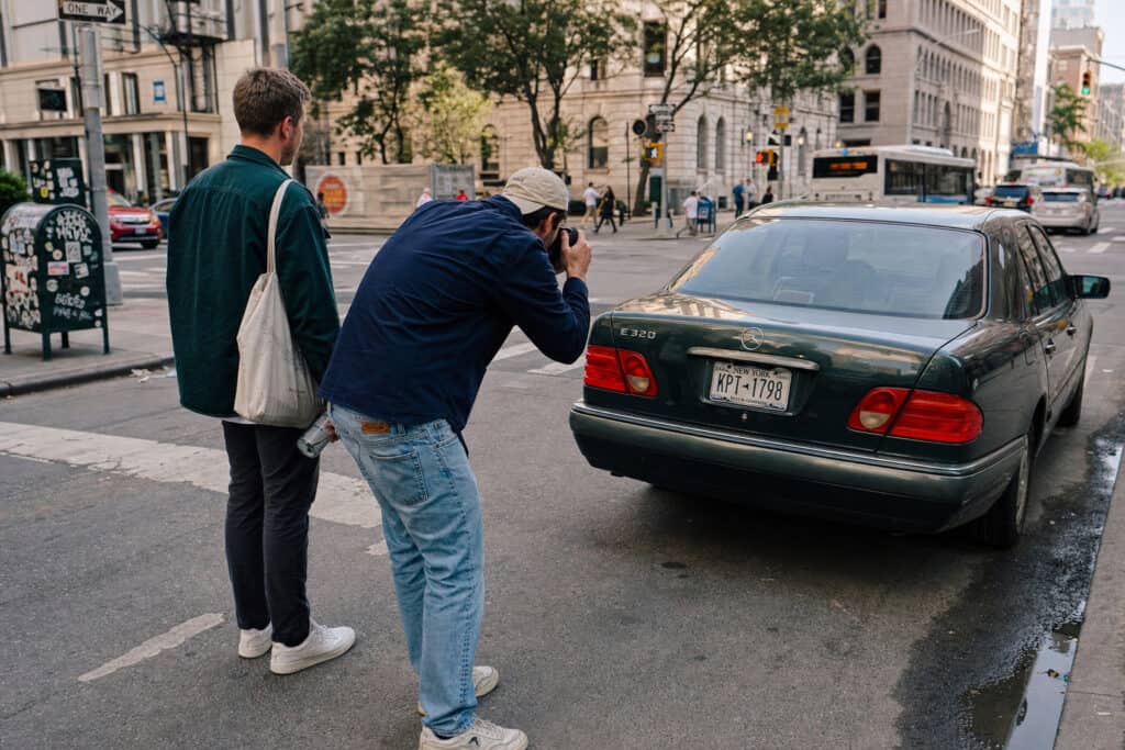 Two pedestrians on a city street near a car, highlighting the importance of safety measures for cyclists and pedestrians to prevent accidents and legal issues.