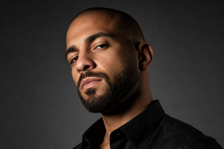Confident man with a clean-shaven head and neatly groomed beard.