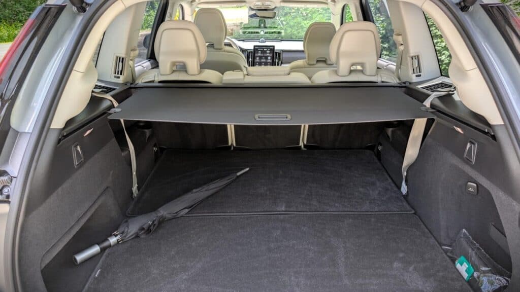 A detailed view of the spacious cargo area inside an SUV, showcasing the clean, black interior with a retractable cargo cover and a safety seatbelt lying on the floor.