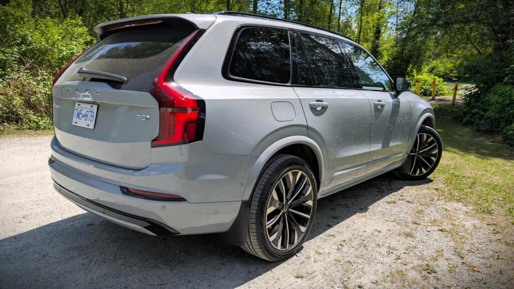 Silver SUV parked on a gravel path surrounded by lush green trees, showcasing a modern design with sleek lines and stylish black alloy wheels, ideal for outdoor adventures and family trips.