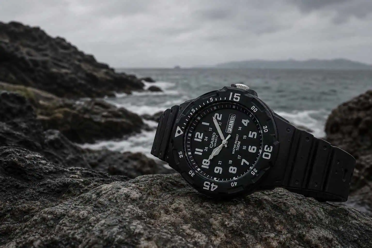 Casio MRW-200H-1EV diver watch on a rocky beach, 100m water resistance.