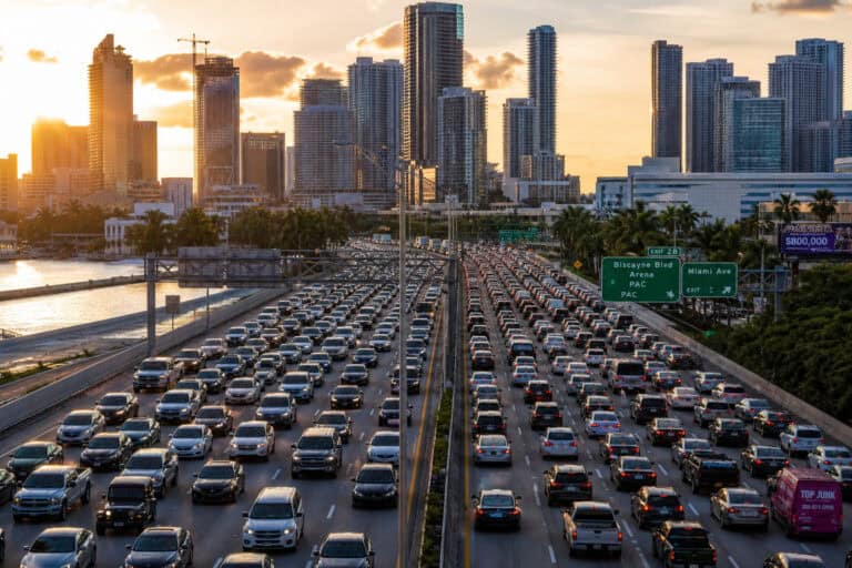 Miami city skyline with high-rise buildings and heavy traffic on the highway during sunset, showcasing urban congestion and modern architecture.
