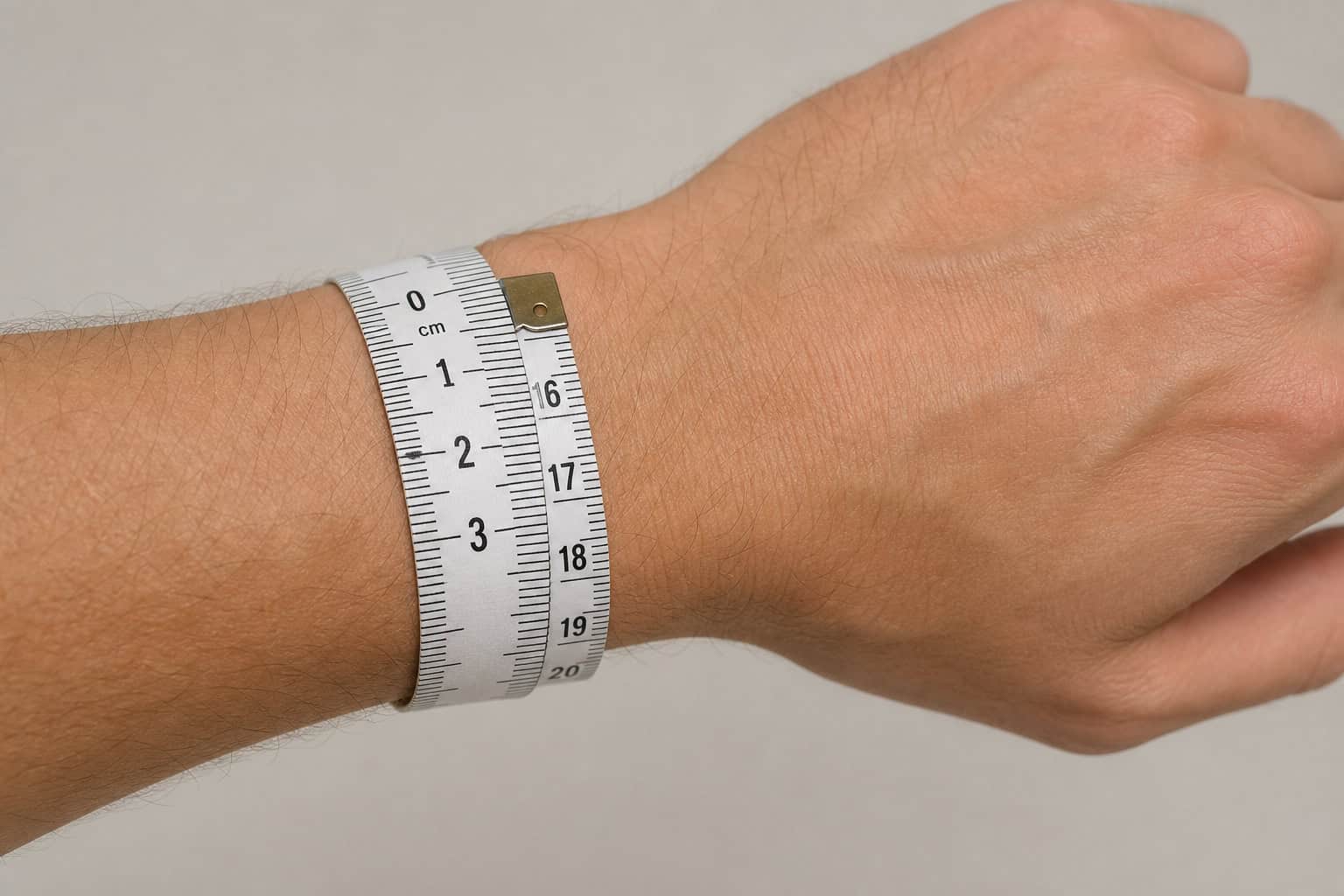 Flexible tape measure wrapped around a man's wrist below the bone to measure circumference.