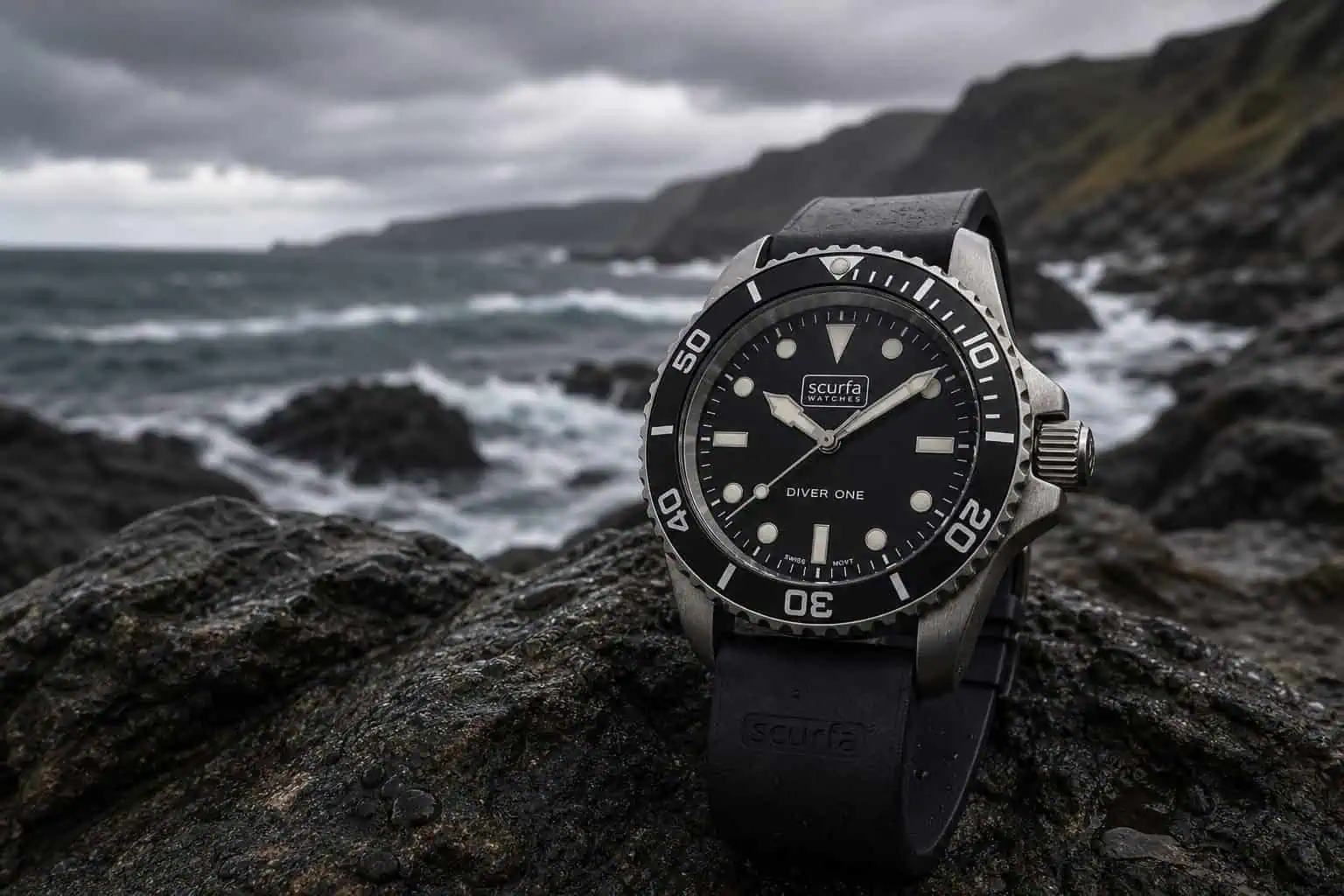 High-quality Scurfa diver watch placed on rocks by the ocean with a rugged coastline and stormy sky in the background, emphasizing durability and adventure.