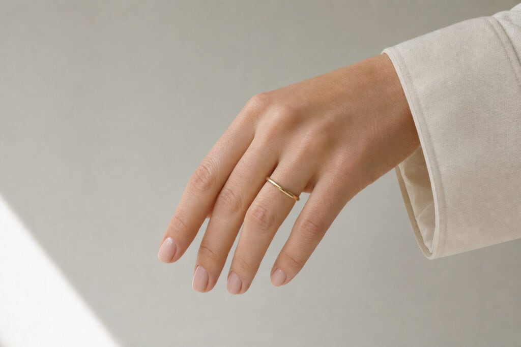 What Are Manly Hands? The Science of Digit Ratio and Why Your Hands Are Fine 6 Close-up of a woman's hand wearing a delicate gold ring on her finger, with a neutral background and casual beige clothing.