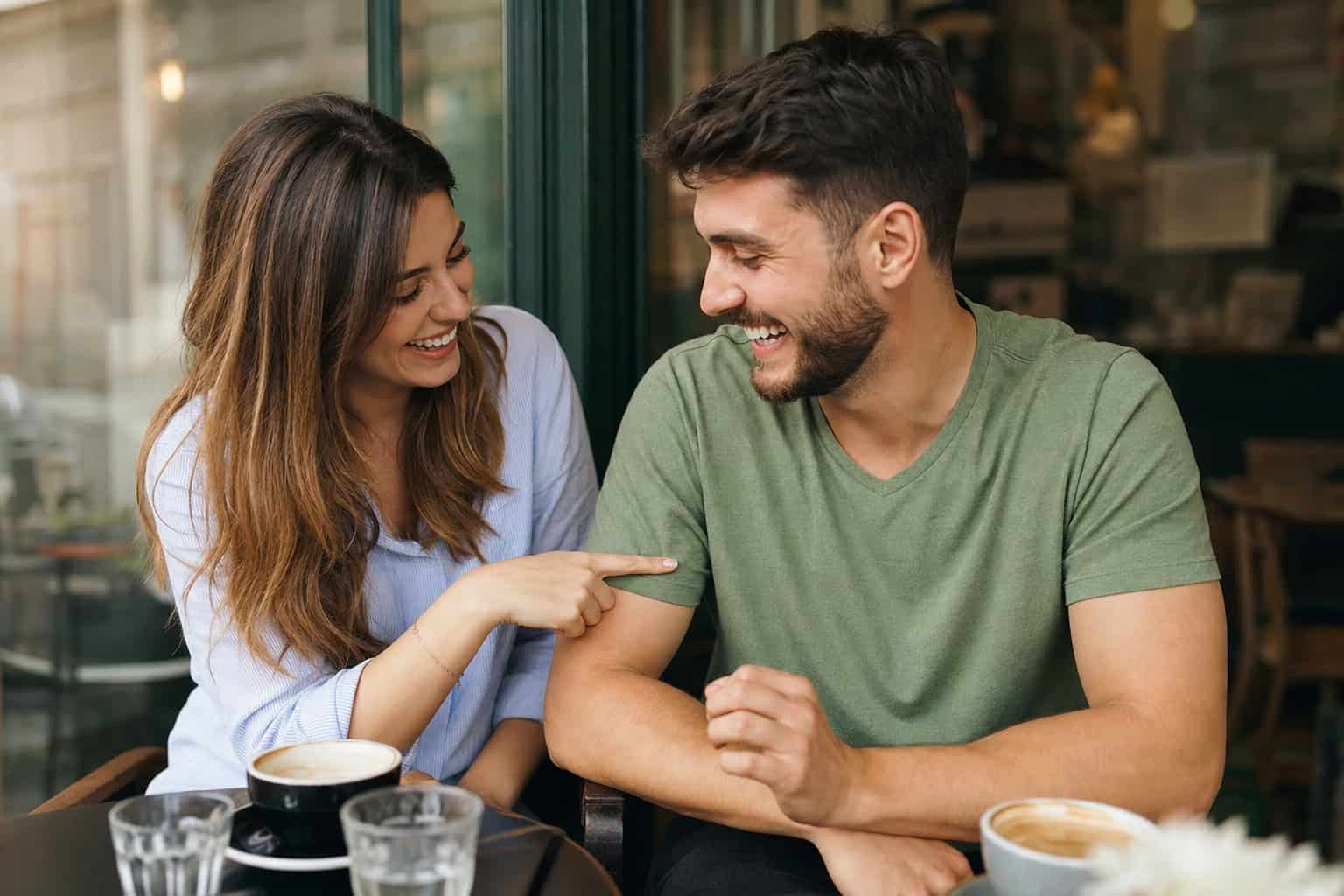 What 'Silly Goose' Means on Dating Apps (And Why It's So Polarizing) 2 Couple laughing together over coffee showing good-natured silliness in a dating context.