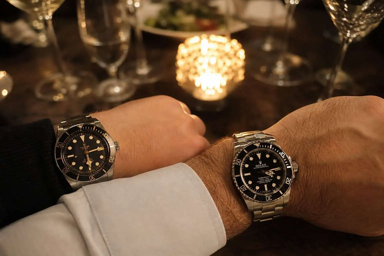 What Is a Poor Man's Rolex? The Real Answer (Tudor, Seiko, Omega) 10 Two wrists at dinner table comparing Tudor Black Bay and Rolex Submariner