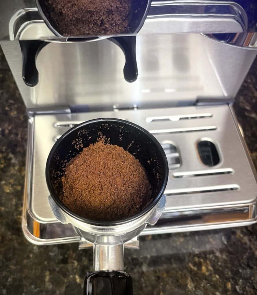 AMZCHEF Espresso Machine Review: 44 Grind Settings and Temperature Control Tested 3 Coffee grounds being ground in an espresso machine with a portafilter attached.
