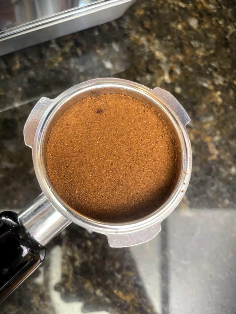 AMZCHEF Espresso Machine Review: 44 Grind Settings and Temperature Control Tested 5 Close-up of freshly ground coffee in an espresso machine portafilter, ready for brewing.