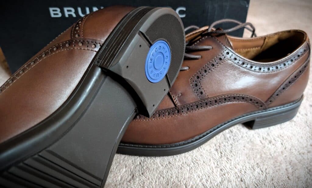 Close-up of men's brown brogue wingtip oxford shoes with a shoehorn inserted, showcasing classic leather craftsmanship.