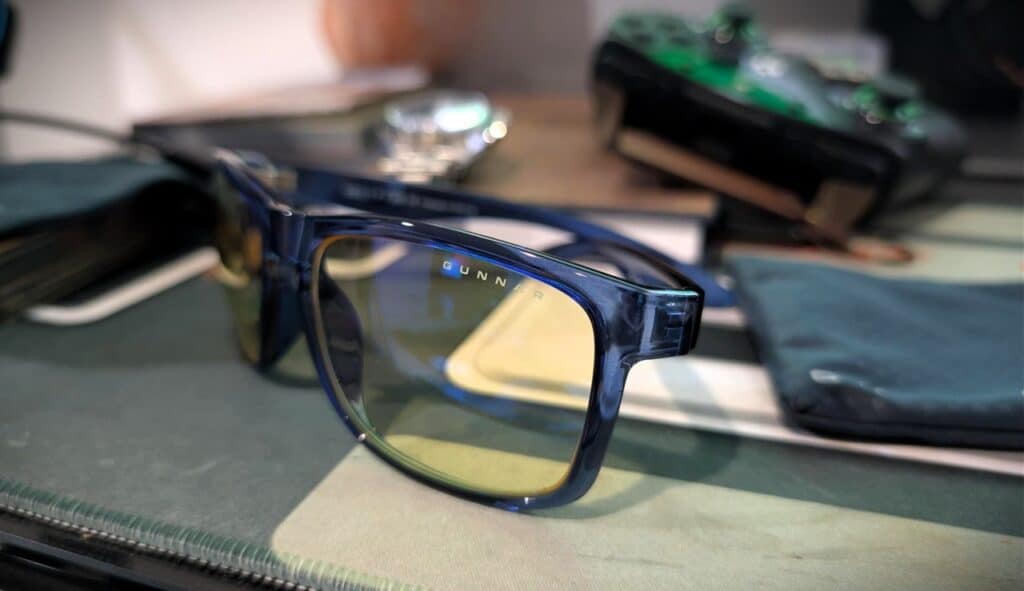 GUNNAR Intercept Review: Crystal Cobalt Owner on Fit, Lenses, and Real Eye Strain Relief 3 GUNNAR Intercept Crystal Cobalt glasses with yellow-tinted lenses on a desk, surrounded by tech accessories and personal items.