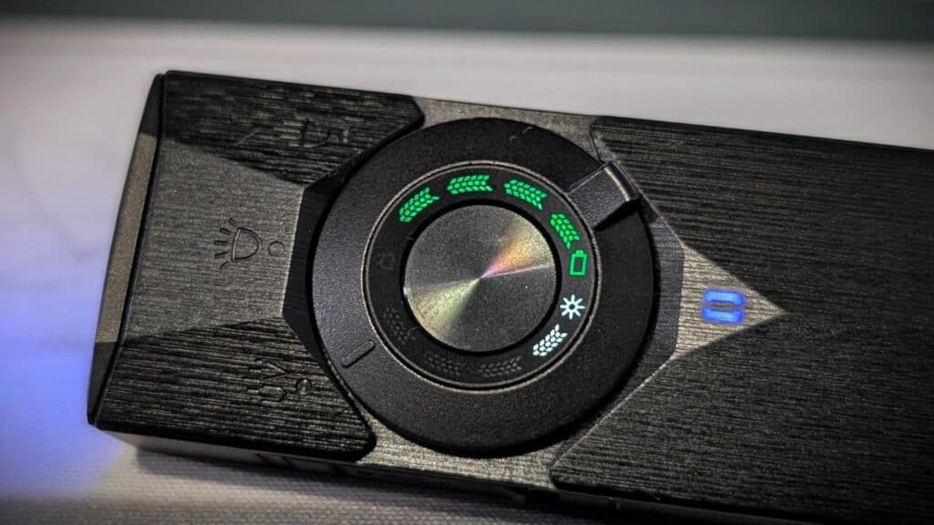 Olight ArkPro Ultra EDC Flashlight Review 2 Close-up of the Olight ArkPro Ultra EDC flashlight's control dial with green indicator lights on a dark wooden surface.