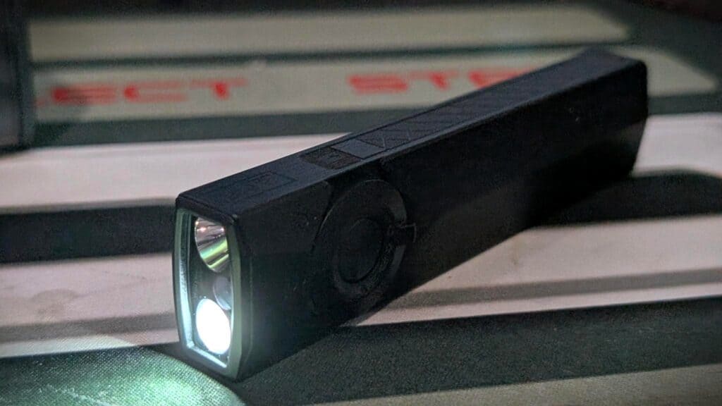 Olight ArkPro Ultra EDC Flashlight Review 10 Olight ArkPro Ultra EDC Flashlight turned on, emitting bright white light, compact black design, ideal for everyday carry and outdoor use.
