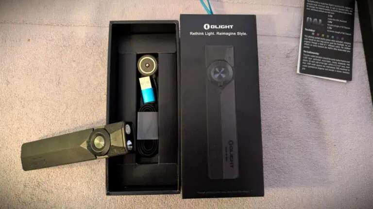 Olight ArkPro Ultra EDC Flashlight with packaging and accessories on a wooden surface.