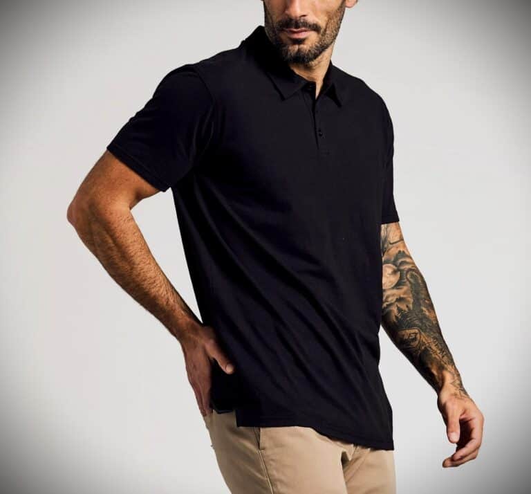 Man wearing a black polo shirt with beige pants, showcasing fit and shoulder highlight, against a plain background.