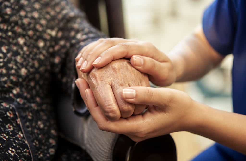 A caregiver gently holding an elderly person's hand, symbolizing compassion and support in senior care.