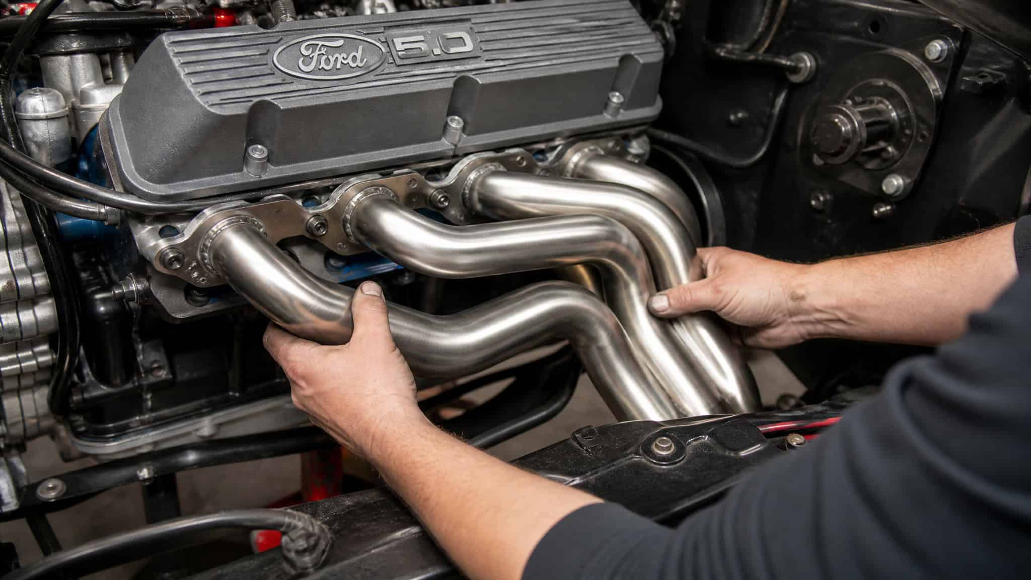 Best F-150 Mods: From Intake to Supercharger, a Tuner's Guide 2 Mechanic installing stainless steel long-tube headers on a Ford 5.0L V8