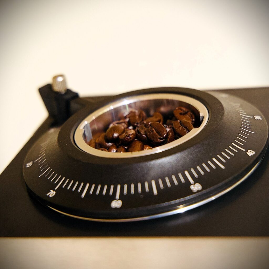 AMZCHEF Commercial Flat Burr Espresso Bean Grinder Review: 90 Settings, Real dial-in Numbers 3 Coffee beans in a flat burr espresso grinder with adjustable dial for precise grinding settings.