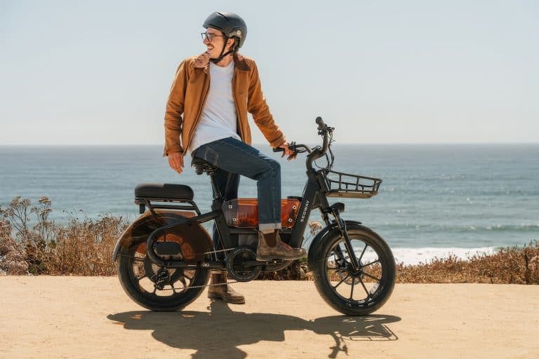 Person riding the Segway MUXI Pro Cargo e-Bike along a coastal path with ocean in the background.