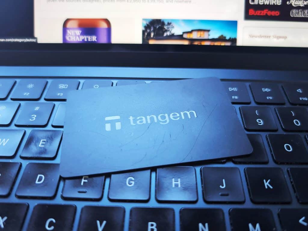 Close-up of a Tangem wallet card placed on a laptop keyboard, with a blurred computer screen in the background.