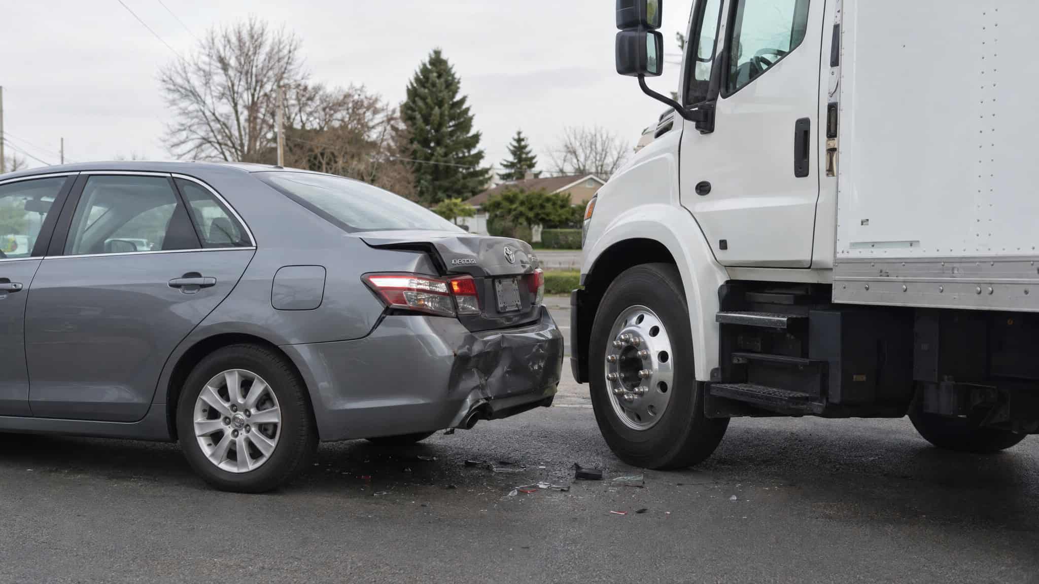 How Much Are Most Personal Injury Settlements? Median Data From 62 Tracked 2026 Cases 3 A gray sedan with rear-end damage after a collision with a large white truck on the road.