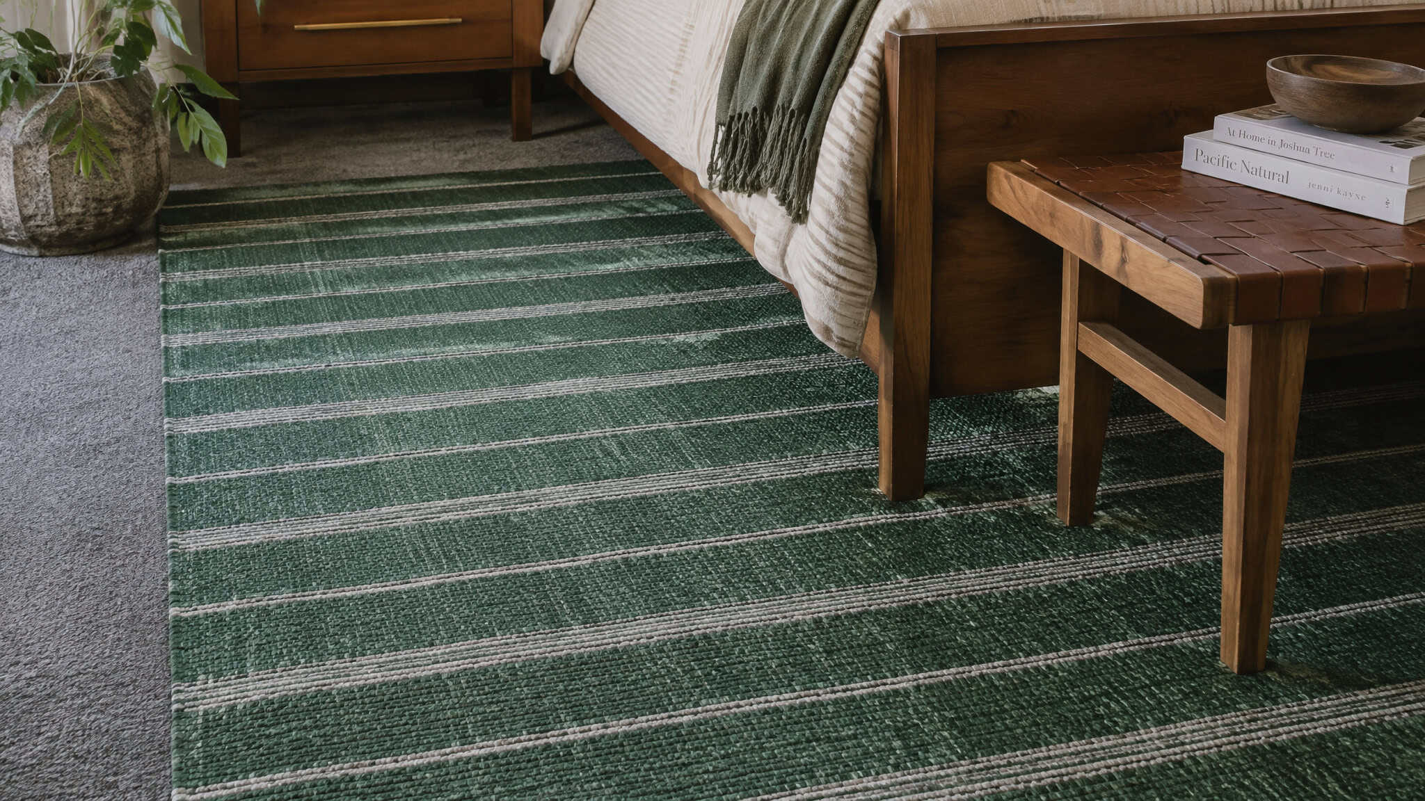 Emerald striped Revival rug layered over gray carpet to add texture in a bedroom