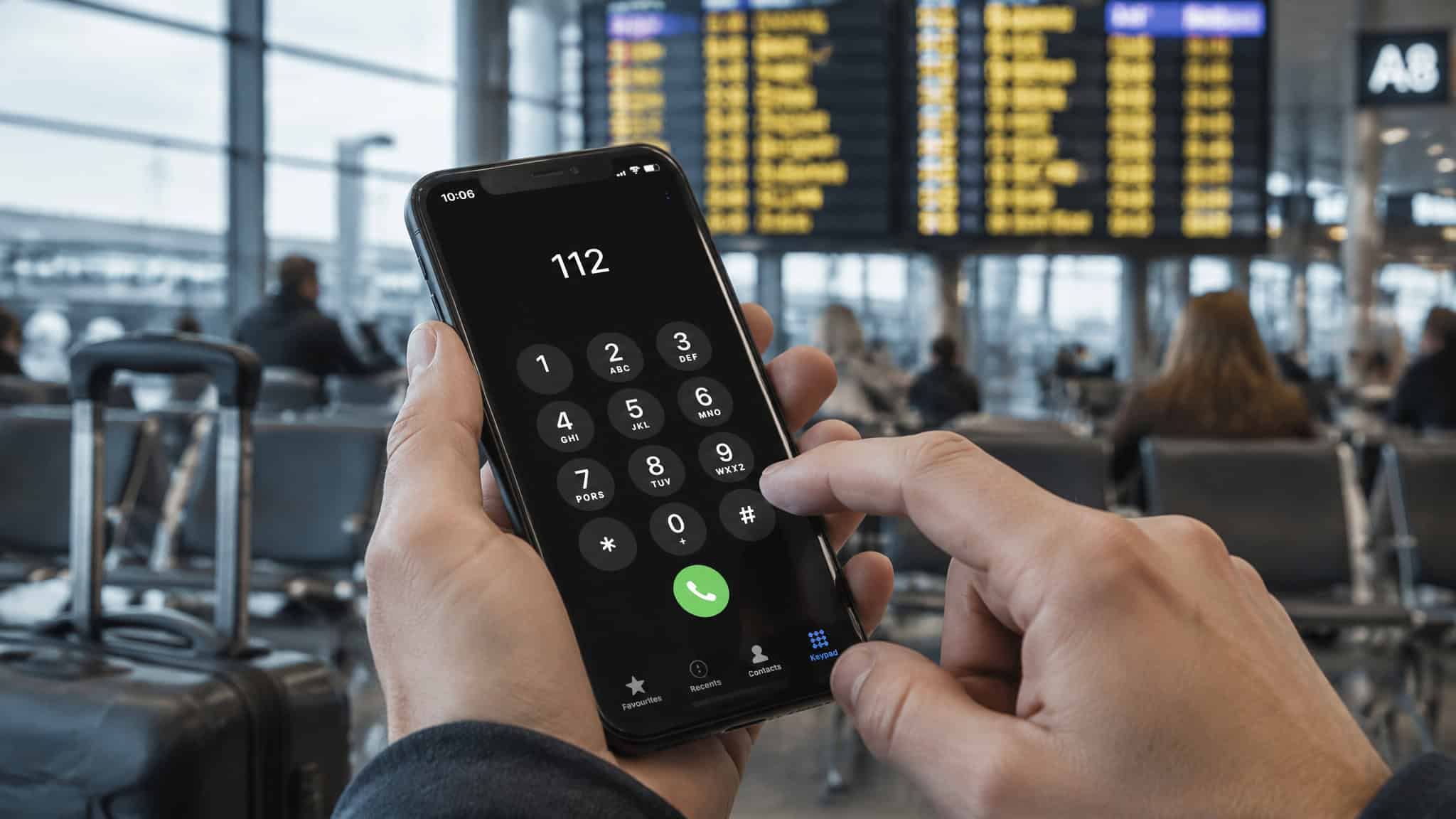 eSIM Not Working Abroad: Troubleshooting Guide — What to Fix at 5, 30, and 60 Minutes 3 Person making an emergency call on a smartphone at an airport terminal with flight information displays in the background.