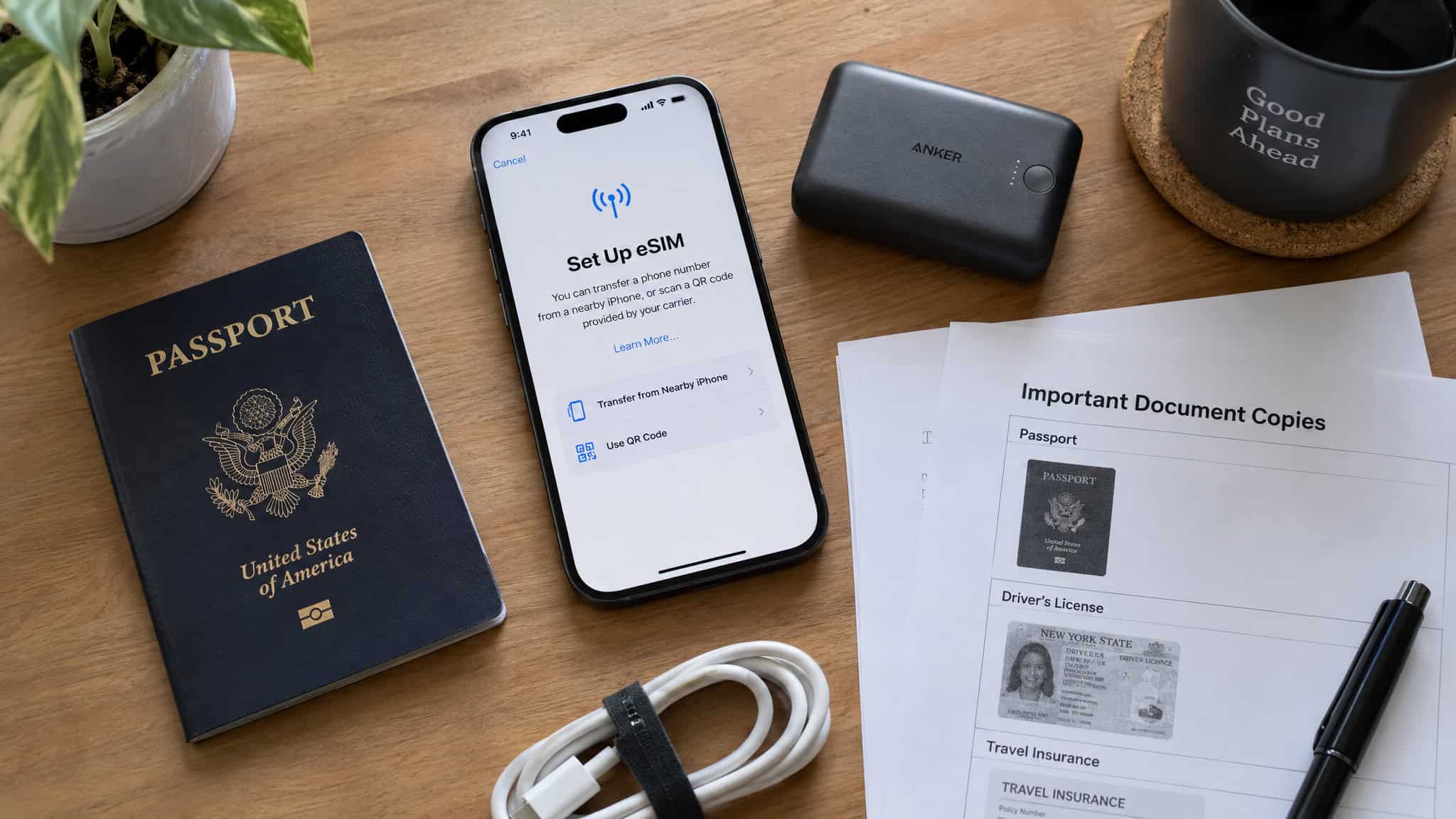 Best Travel Hacks: 20+ Tested Tips From 20 Years of Frequent Travel (and 4 That Don't Work) 3 Travel essentials including a US passport, smartphone, portable charger, important documents, and a pen on a wooden surface.