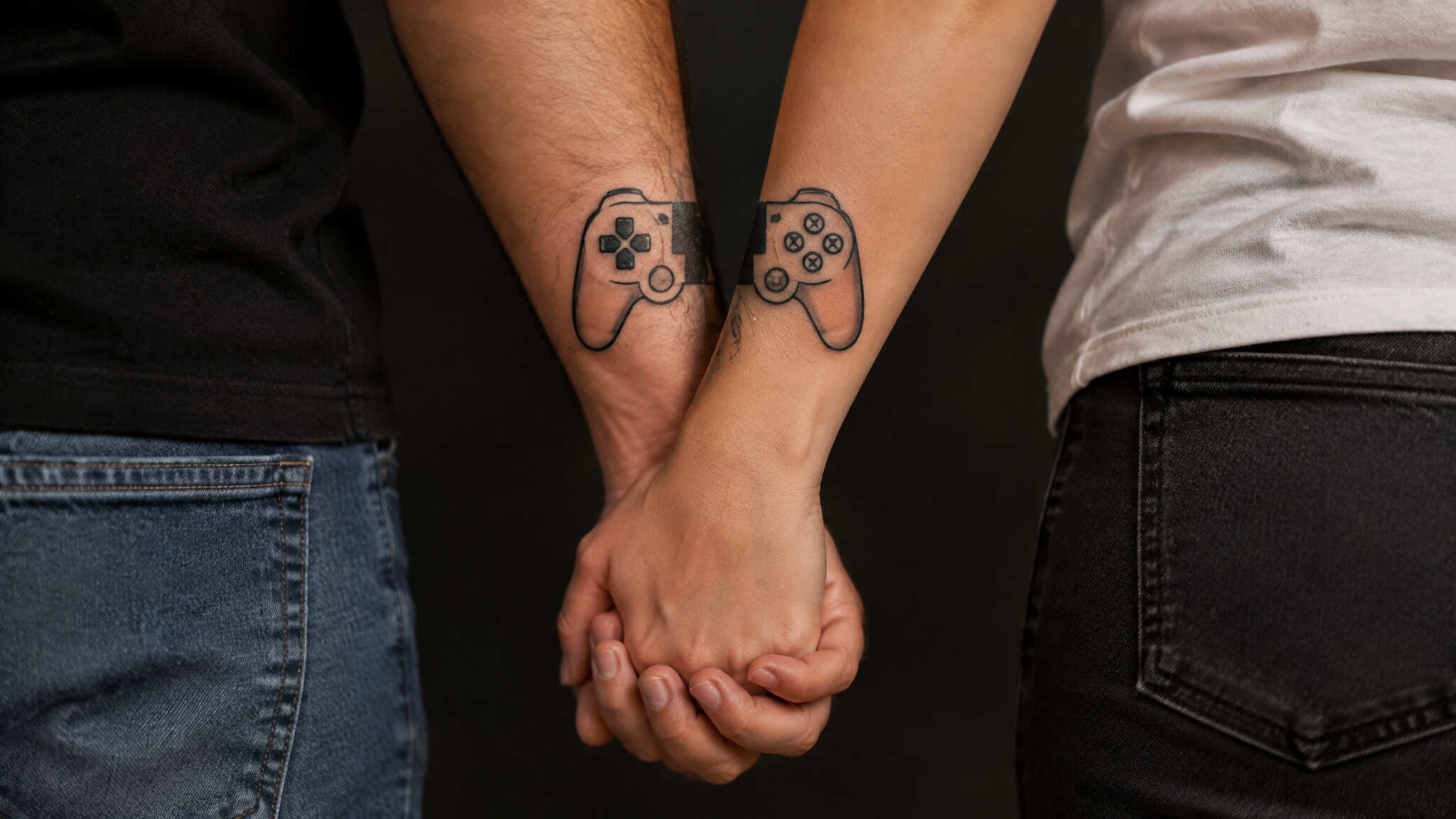 Gamer couple tattoos with matching split controller halves forming one controller when hands meet