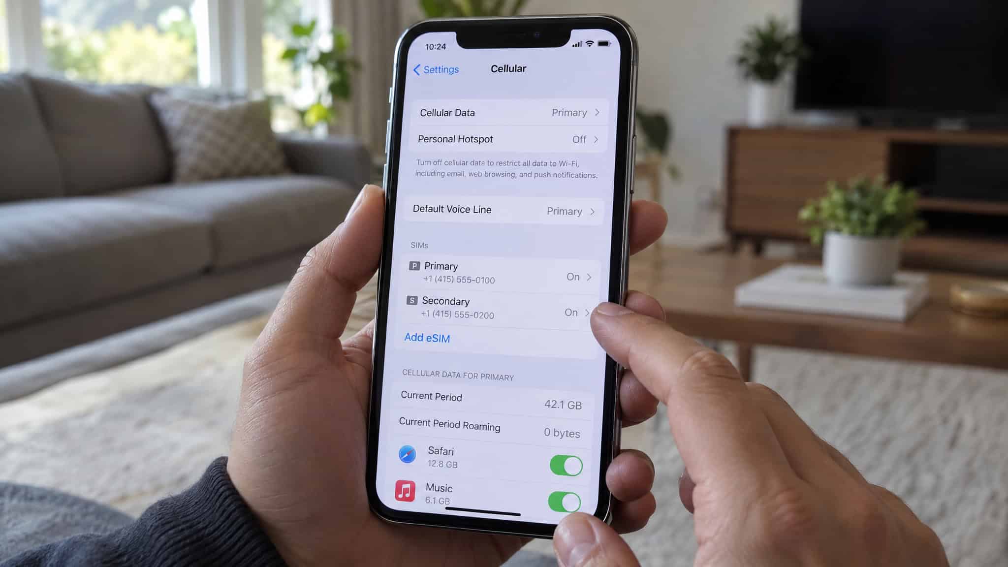 How to Use an eSIM on iPhone for International Travel (and the Toggle That Stops Surprise Roaming Bills) 3 Close-up of a person adjusting mobile data settings on an iPhone in a modern living room.