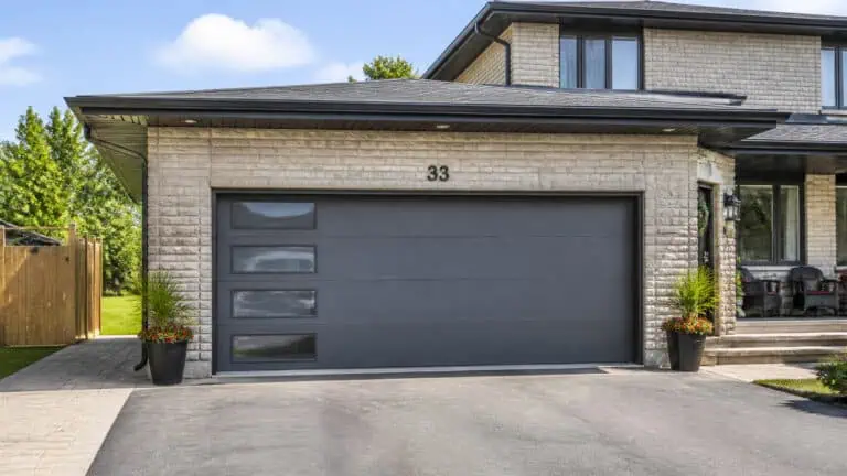 Contemporary house featuring a sleek black garage door, brick exterior, and landscaped front yard with potted plants, located at 33.