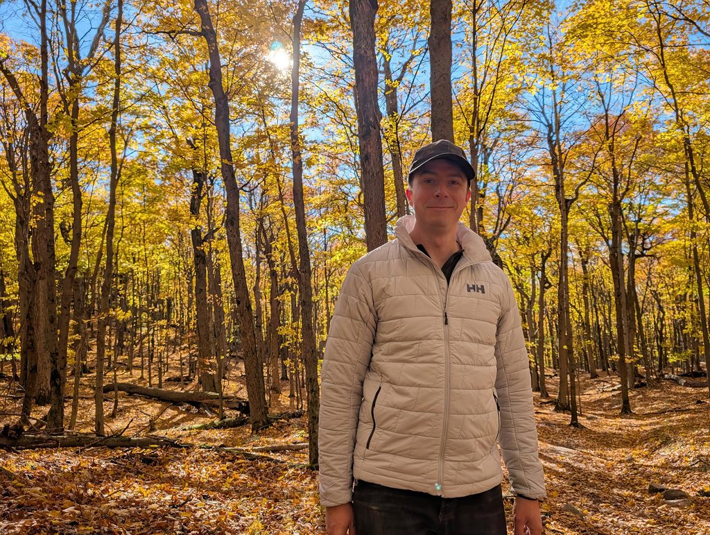 Helly Hansen Men's LIFALOFT™ Insulator Jacket Review: Three Weeks In, One Layering Lesson 2 Man wearing Helly Hansen insulated jacket in a sunlit autumn forest with yellow leaves.