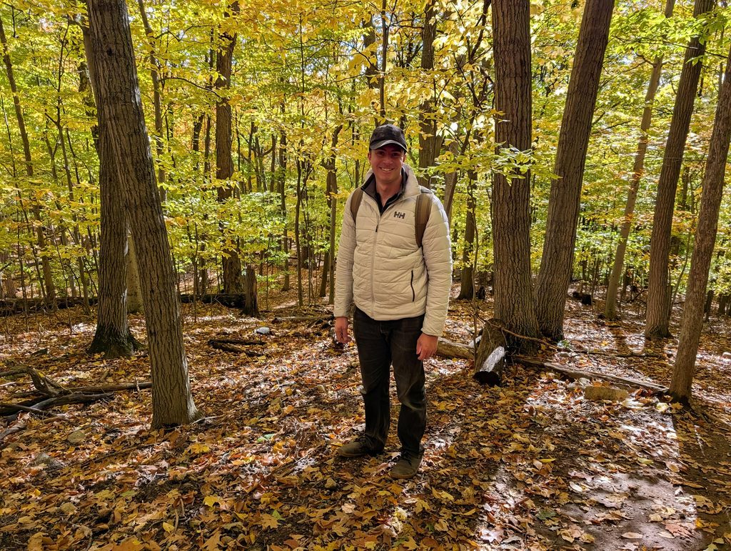 Helly Hansen Men's LIFALOFT™ Insulator Jacket Review: Three Weeks In, One Layering Lesson 4 Woman hiking in a forest wearing a Helly Hansen LIFALOFT insulator jacket during fall.