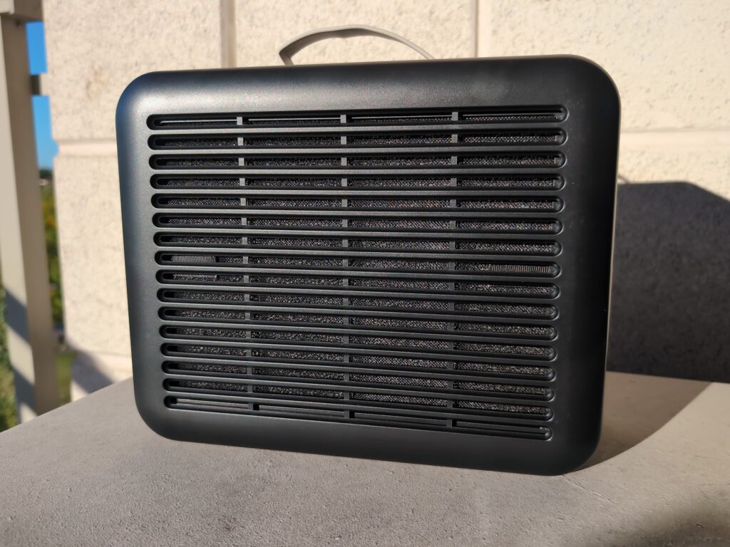 PuroAir 100i HEPA Smart Air Purifier Review: What the 240's Failed Testing Means 2 Black PuroAir 100i HEPA smart air purifier with horizontal vents on a gray surface outdoors.