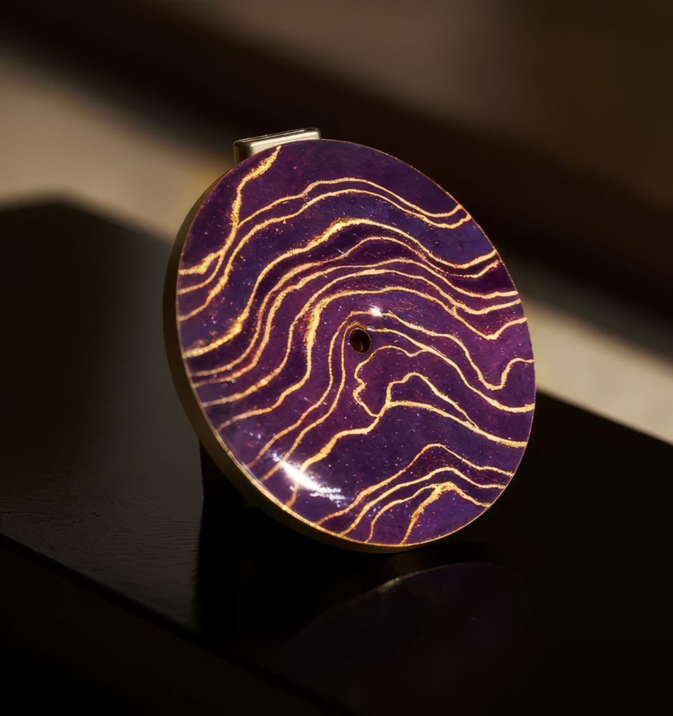 Close-up of a watch dial with hand-lacquered Rizière design in purple and gold, showcasing intricate wavy patterns.