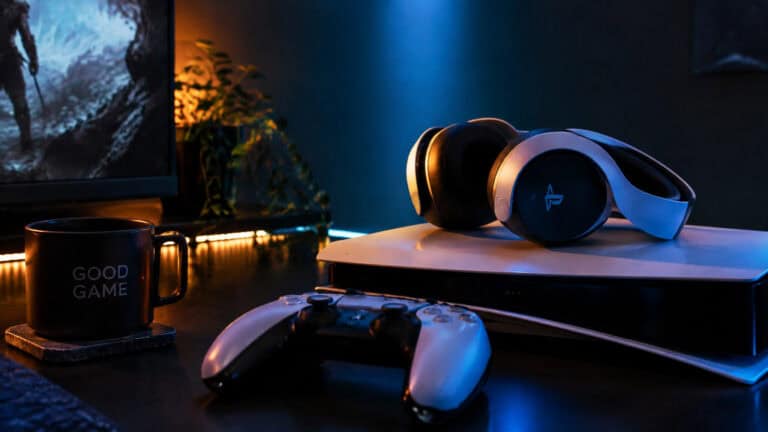 A gaming setup featuring a PlayStation controller, gaming headphones, and a mug with 'Good Game' written on it, illuminated by ambient lighting.