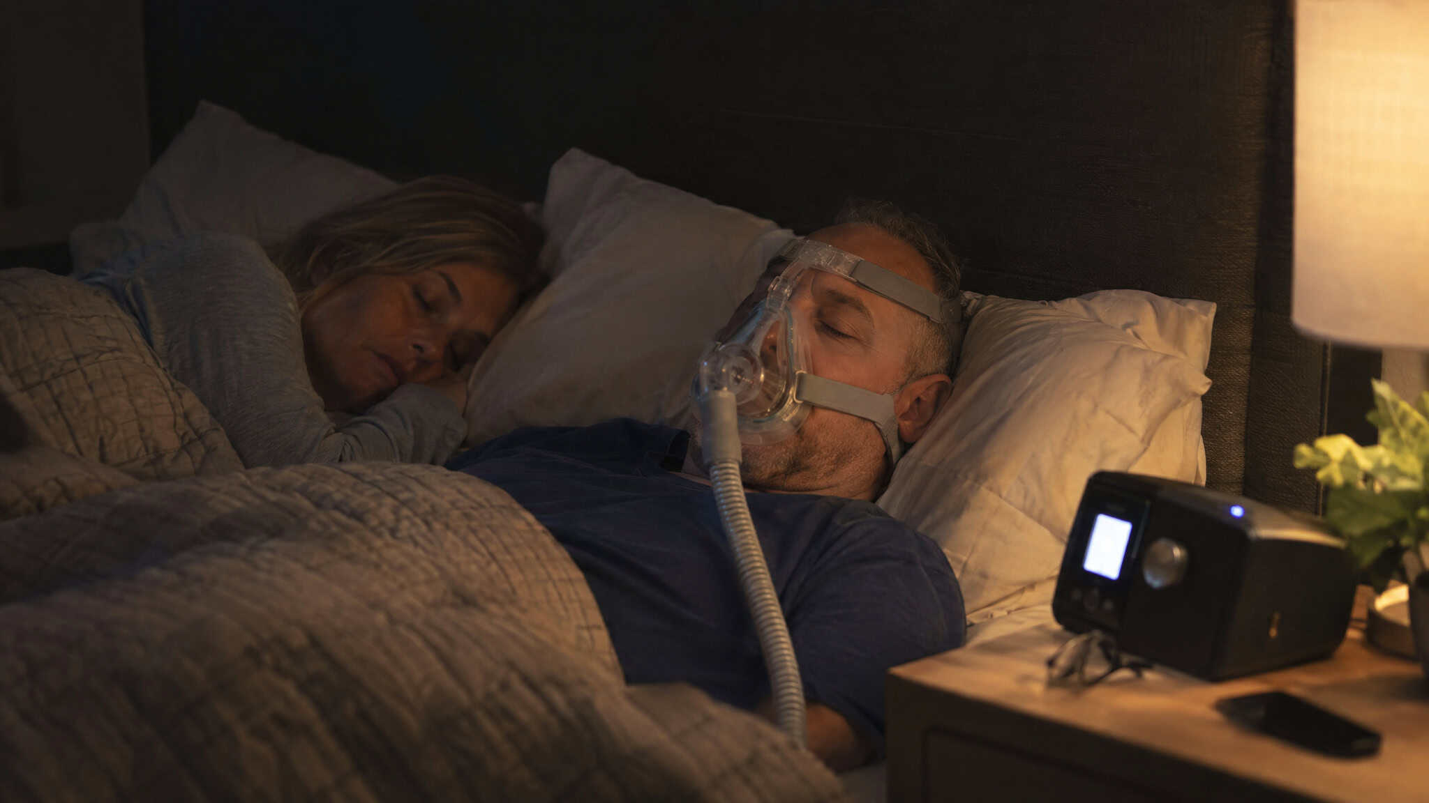 Should a 45 Year Old Man Take Testosterone? What Two Morning Blood Tests Decide 3 A man sleeping peacefully with a CPAP machine on his face, in a cozy bedroom setting, highlighting sleep therapy for sleep apnea.