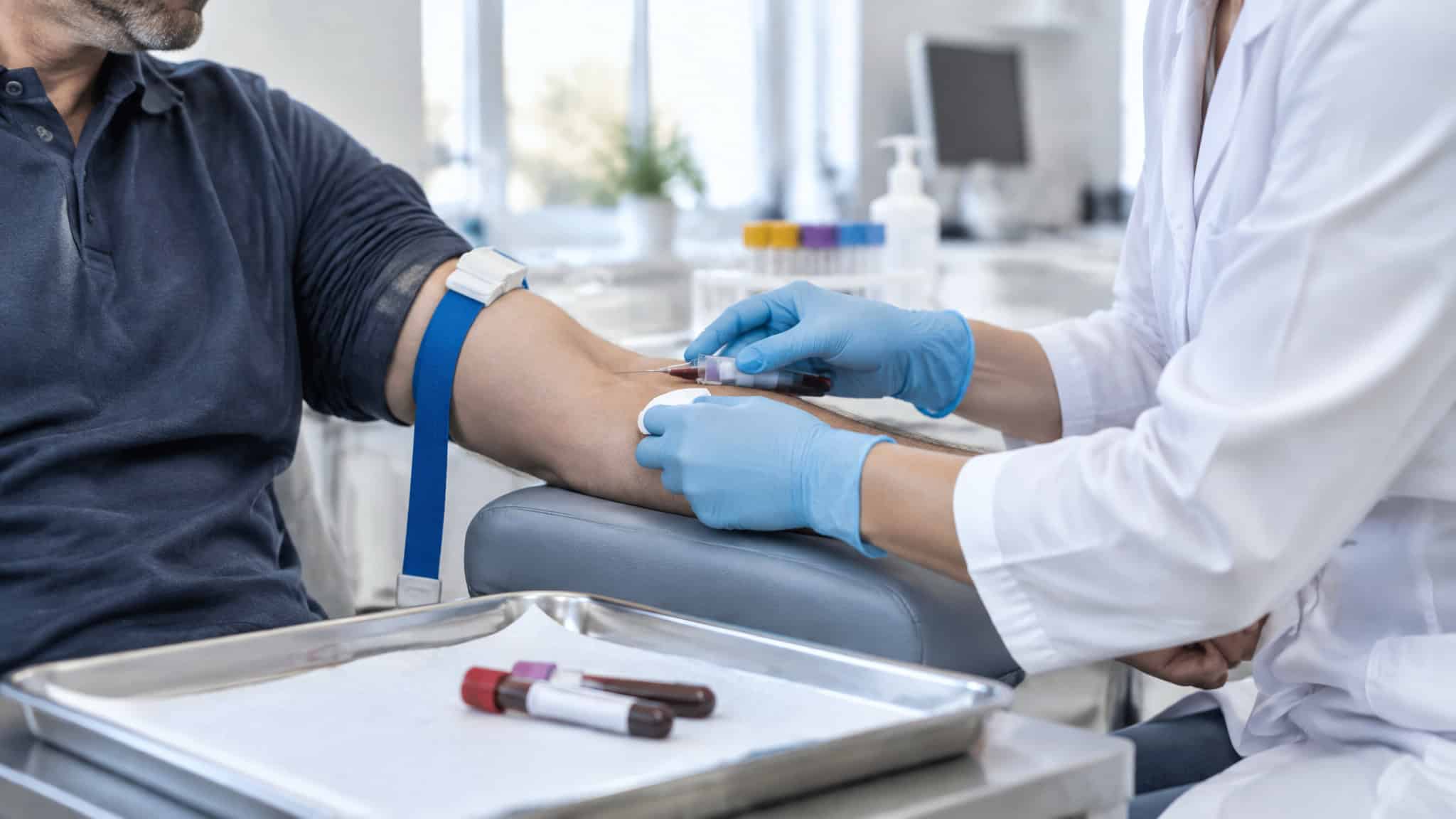 Should a 45 Year Old Man Take Testosterone? What Two Morning Blood Tests Decide 2 Healthcare professional drawing blood from a patient for testing in a clinical setting.